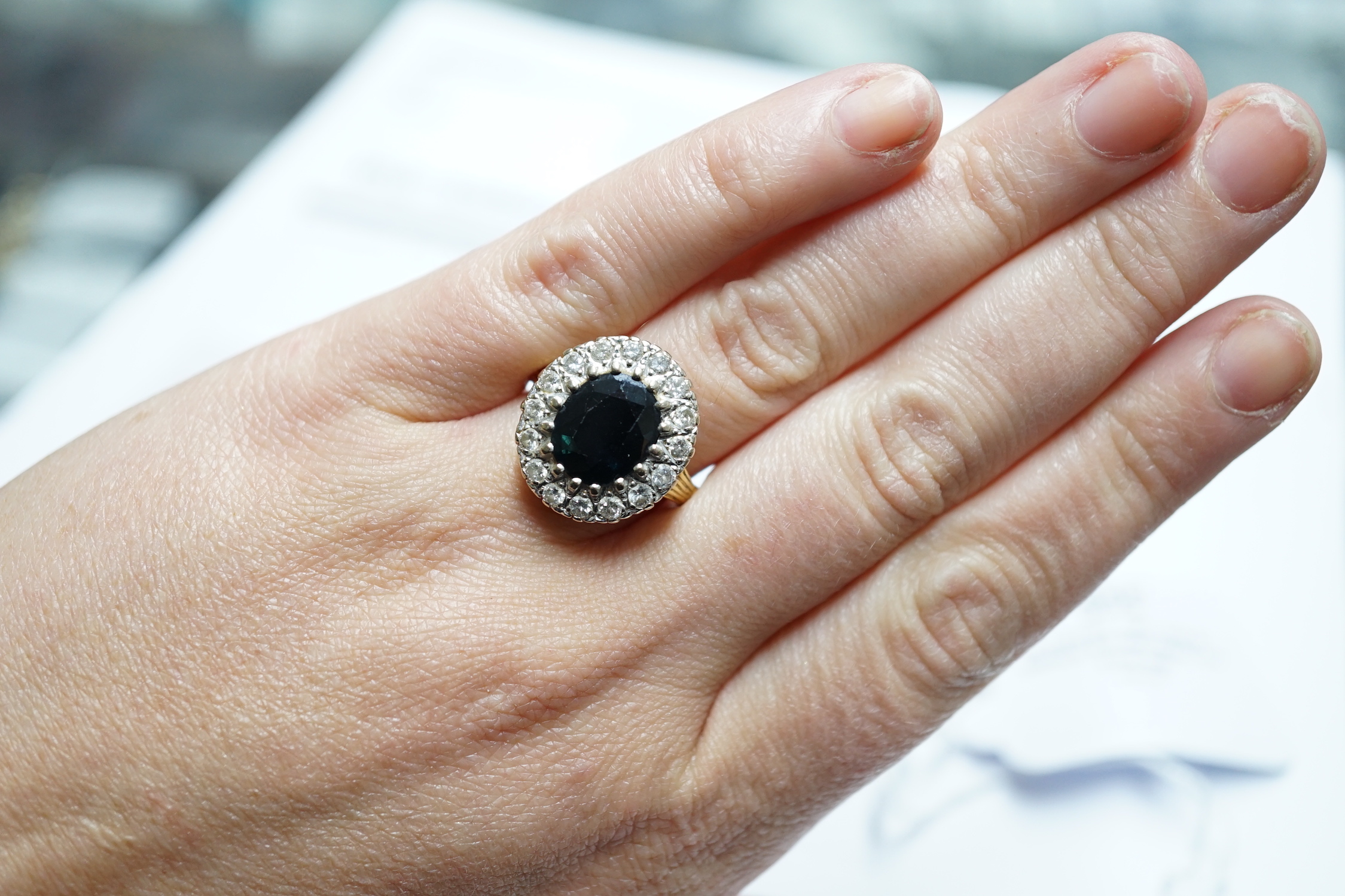 A 1970's? 18ct gold, single stone oval cut sapphire and illusion set diamond cluster ring, size O/P, gross weight 8.2 grams.